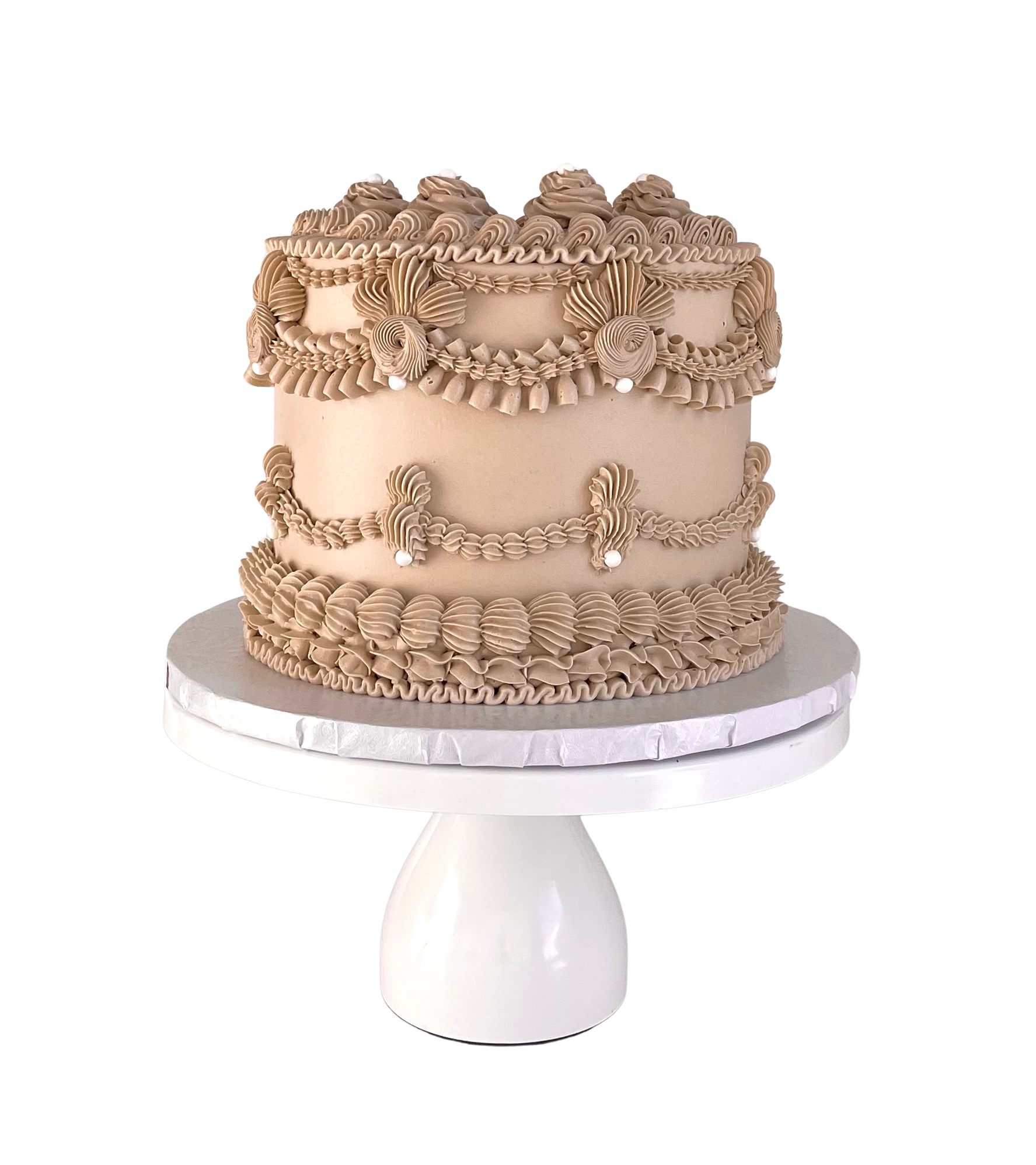 Decorative cake with intricate designs on a white stand against a white background